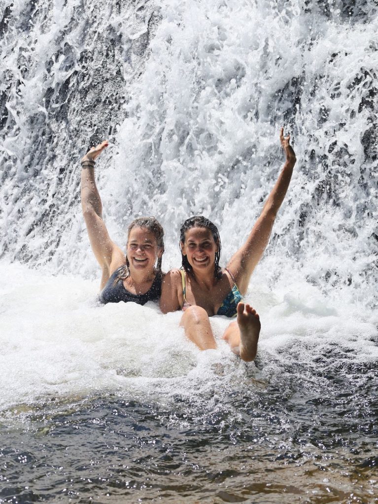 duas mulheres embaixo da cascata da cachoeira do Paquetá