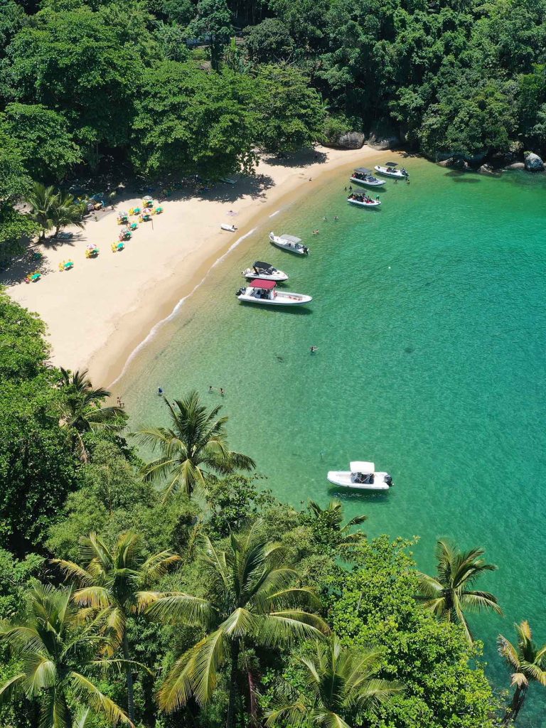 Vista aérea da praia do Eustáquio em Ilhabela com águas cristalinas e barcos na praia