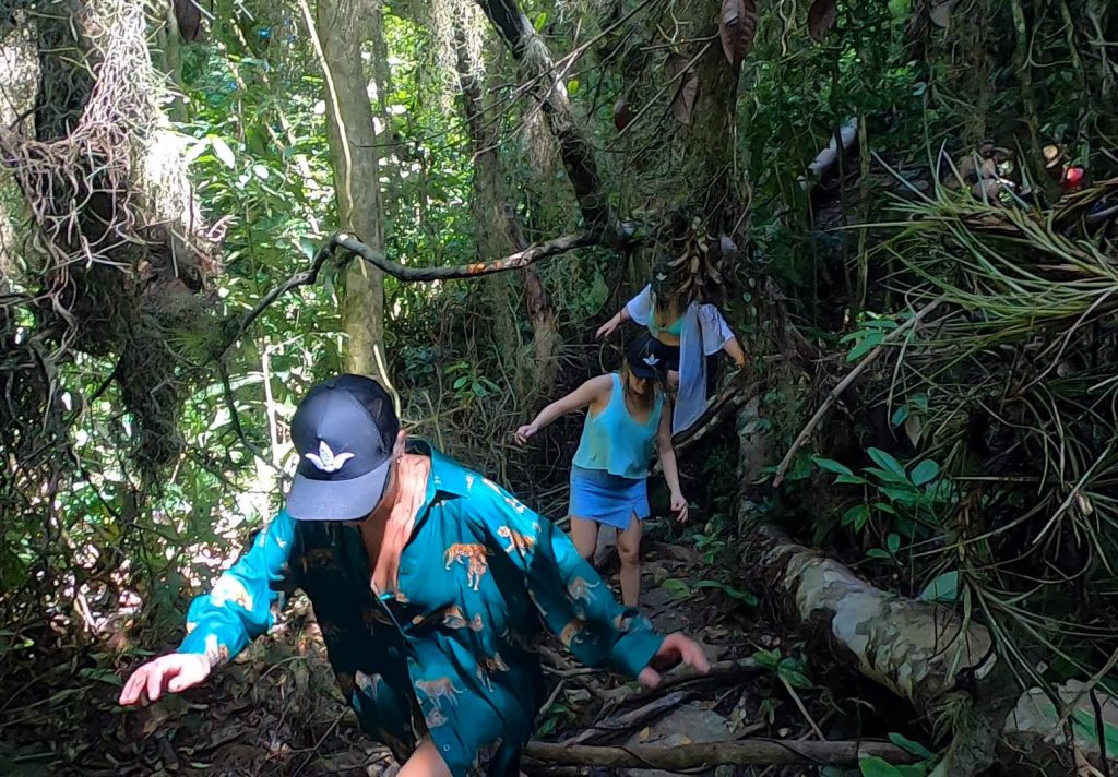 Pessoas na trilha em meio a mata atlântica em Ilhabela indo para a cachoeira do Paquetá.